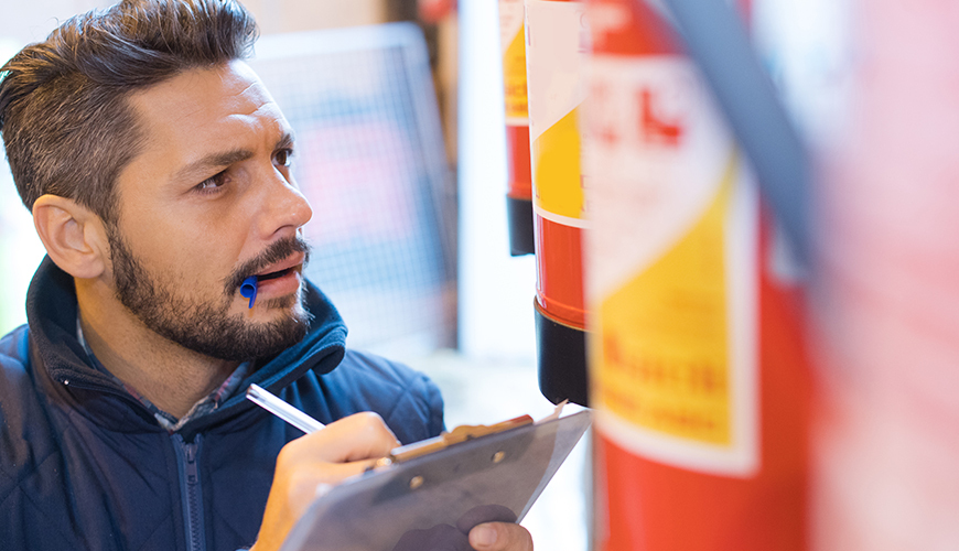 Member of staff inspecting fire extinguisher